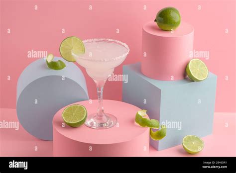 Glass Of Margarita Cocktail And Fresh Limes On Pink Background Stock