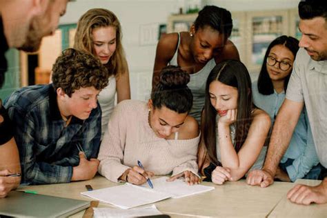 Female Studying With Friends While Professor Assisting In Classroom