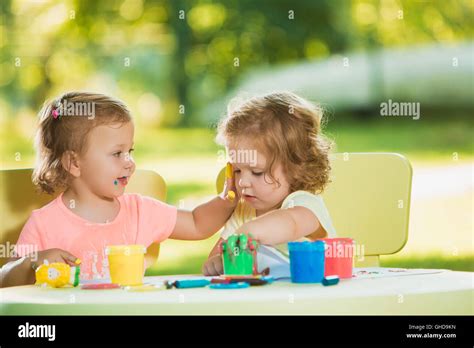 Two Year Old Girls Painting With Poster Paintings Together Against