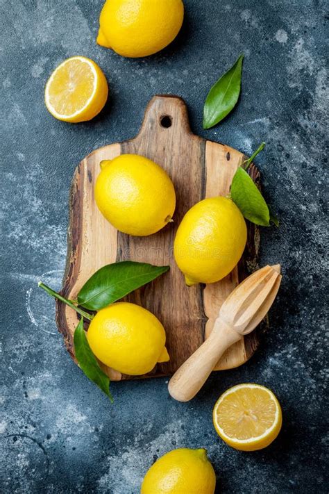 Fresh Ripe Lemons With Leaves On Wooden Board Over Black Stone