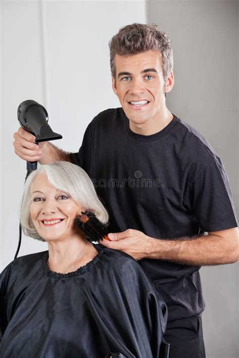 Les Cheveux De Straightening Female Client De Coiffeur Image Stock