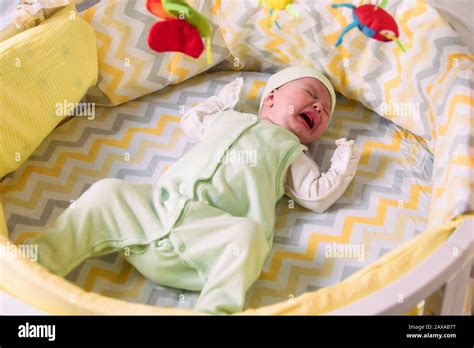 a cute baby is lying in a crib and crying because of colic Stock Photo - Alamy