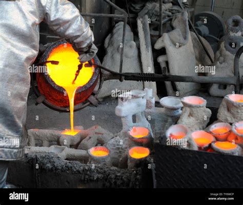 Bronce fundido se vierte en moldes de metal durante la fundición de la