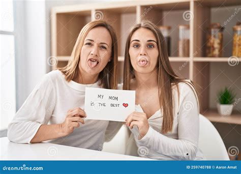 Middle Age Mother And Young Daughter Holding My Mom Is The Best Banner Sticking Tongue Out Happy