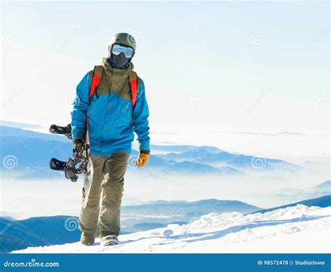 Young Snowboarder In Helmet Walking At The Top Of A Mountain At Golden