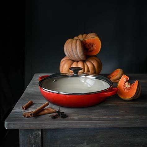 A Red Pan Sitting On Top Of A Wooden Table Next To Pieces Of Fruit And