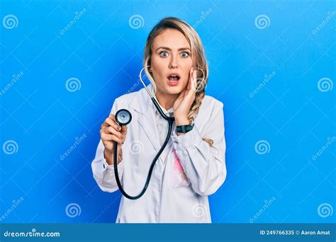 Beautiful Young Blonde Doctor Woman Holding Stethoscope Afraid And