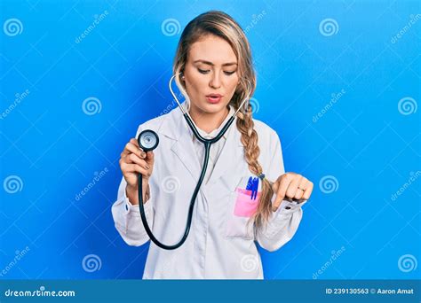 Beautiful Young Blonde Doctor Woman Holding Stethoscope Pointing Down