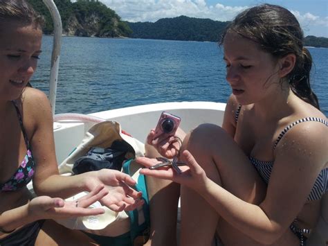 two girls sitting on a boat looking at their cell phones