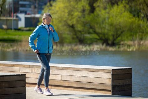 Mature Woman Jogging In The Park And Looking Concentrated Stock Photo