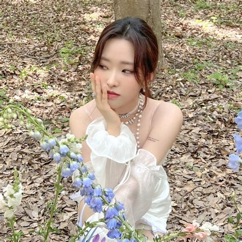 A Woman Sitting On The Ground Next To Flowers