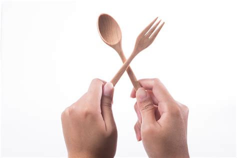 Hand Holding Wooden Spoon And Fork Isolated On White Background Stock