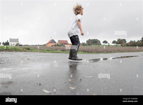 Boy Jumping Into A Puddle Stock Photo Alamy