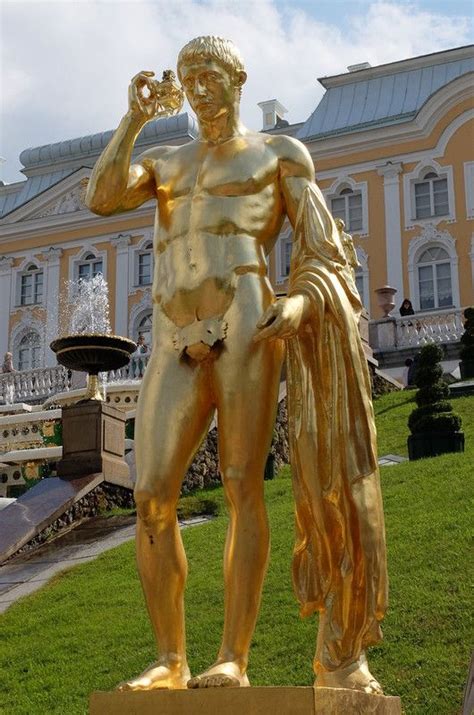 A Gold Statue Is Standing In Front Of A Building With A Fountain And