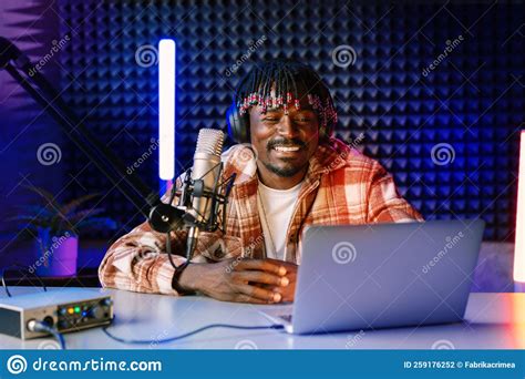 African Radio Host Sitting At Desk Recording In Studio With Microphone