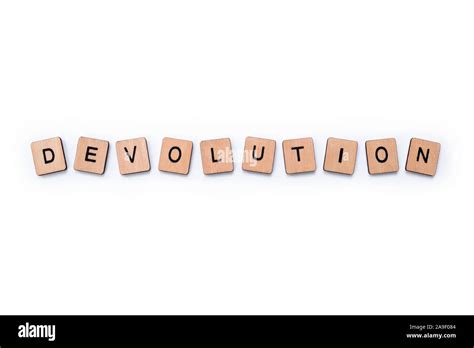 The Word Devolution Spelt With Wooden Letter Tiles Over A Plain White