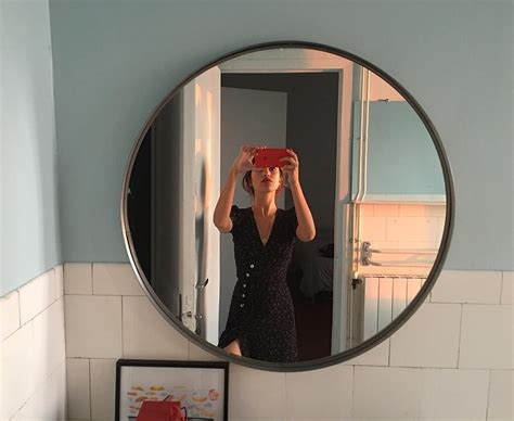 A Woman Taking A Selfie In Front Of A Bathroom Mirror With A Red Camera