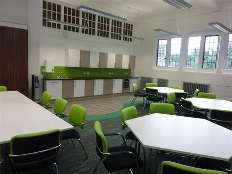 Modern School Staffroom With Green Accents And Hexagonal White Desks