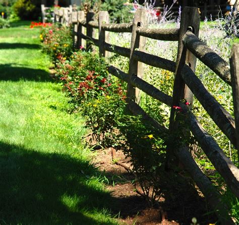 A Wooden Fence Is Surrounded By Flowers And Grass