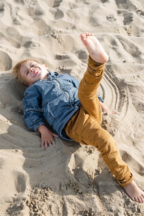 Little boy makes a sand angel on the beach. Stock Photo by slavazolotko