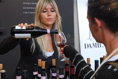 Vinho Tinto De Derramamento Da Mulher Loura Da Garrafa Ao Vidro Do