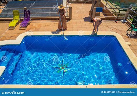 Two Female Friends And Lesbian Couple Cleaning A Swimming Pool Together Dressed In Sundress And