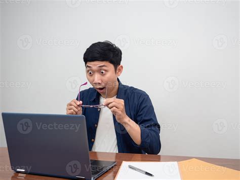 Businessman take off his glasses feels shocked looking at laptop on