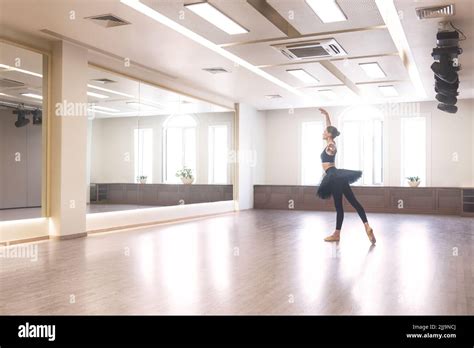 A Graceful Ballet Dancer In A Black Tutu Performs Ballet Exercises In Front Of A Mirror In The