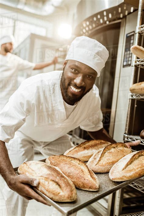 Happy African American Baker Taking Bread Loaves From Oven At Baking