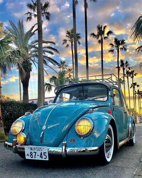 An Old Blue Car Parked On The Side Of The Road With Palm Trees In The