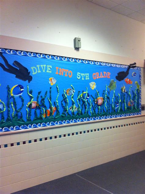 an underwater themed bulletin board hangs on the wall in a school hallway with tile flooring