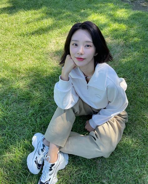 A Woman Sitting In The Grass With Her Hand On Her Chin