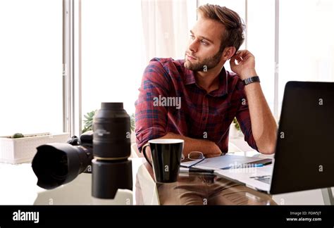 Entrepreneurial Photographer Looking Off Camera At His Desk Stock Photo