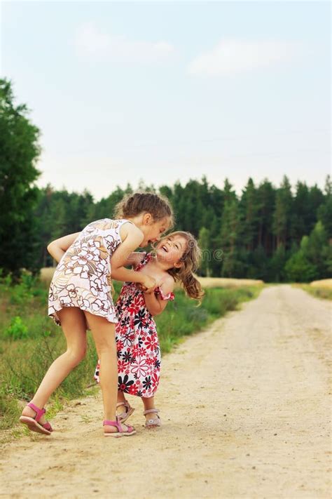 Duas Meninas Bonitas Que Sorriem E Que Jogam No Campo Em W Imagem De