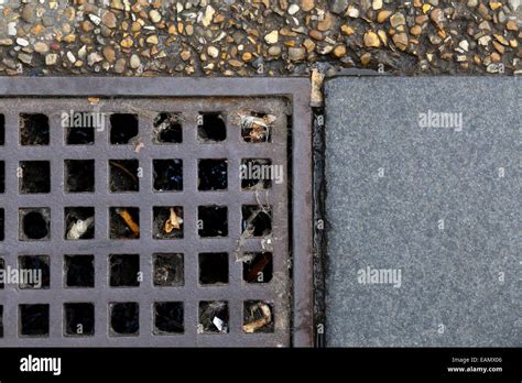 Metal Grill Drain Cover In A Pathway Of Asphalt And Pavement Grey Stock