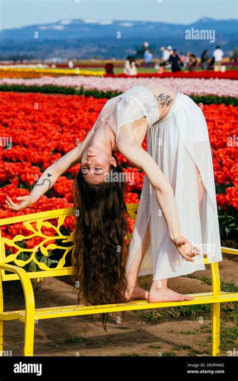 Long Haired Brunette Bending Over Backwards On Bench In Front Of Tulip