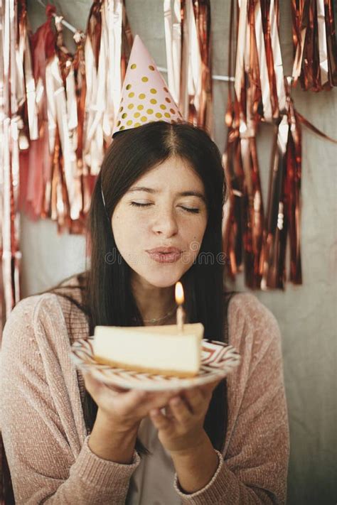 Stylish Happy Woman In Party Hat Blowing Burning Candle On Piece Of