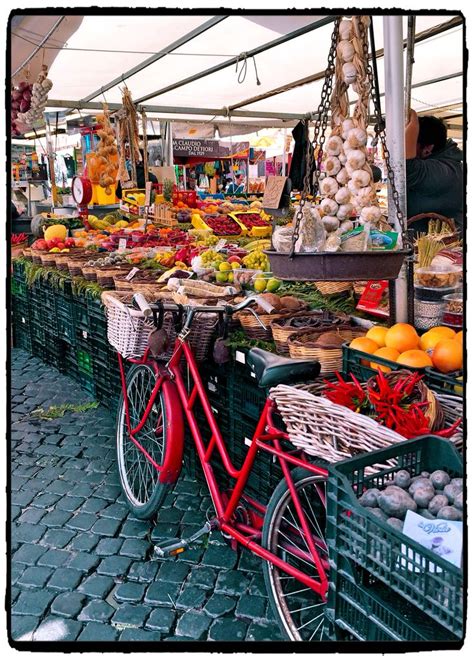 a red bike parked next to a table filled with fruits and vegetables