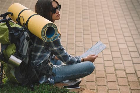 Backpacker Femenino Joven En Las Gafas De Sol Que Se Sientan En Hierba