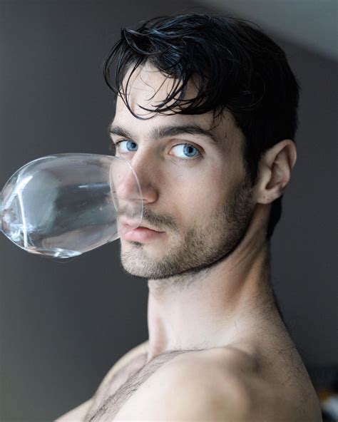 A Man With No Shirt Holding A Water Bottle In His Mouth