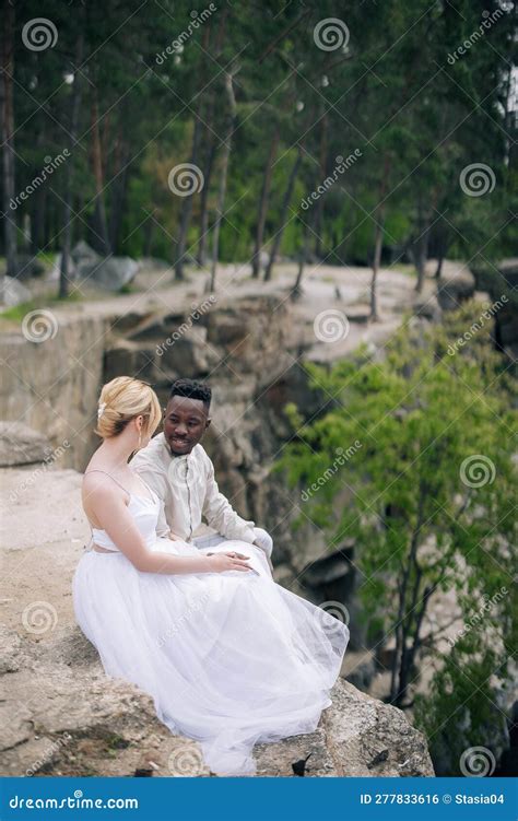 Young Interracial Couple Newlyweds Sits On Rock And Talks Against