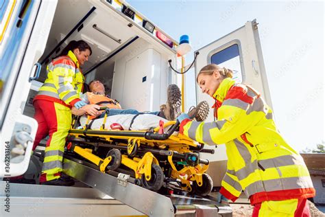 Paramedics Putting Injured Man On Stretcher In Ambulance Car Stock