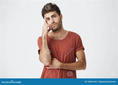 Young Unhappy Dark Skinned Stylish Spanish Man In Red T Shirt Holding