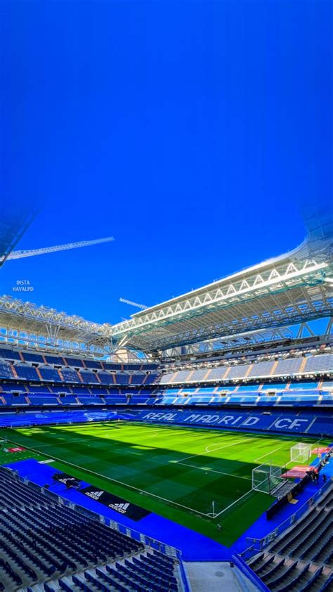 An Empty Soccer Stadium Filled With Lots Of Blue Seats And Green Grass