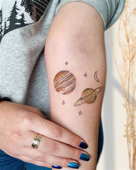 A Woman S Arm With Tattoos On It And Planets Painted On The Back Of Her Arm