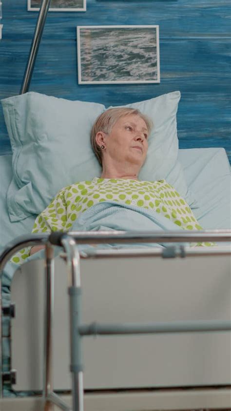 Woman With Disease Resting In Hospital Bed With IV Drip Bag Stock Image