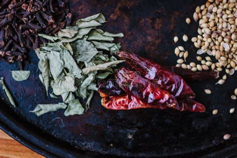 Green Curry Leaves On Black Metal Plate Surrounded By Other Spices