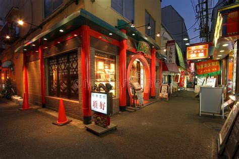 An Empty Street At Night With Shops On Both Sides And Signs In The