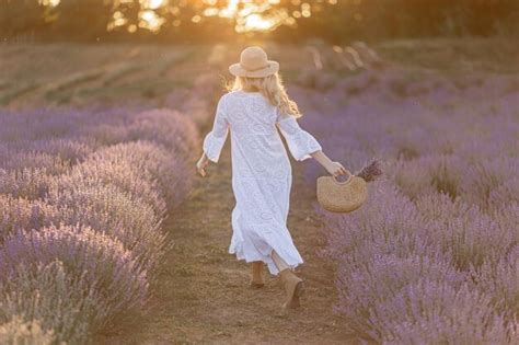 Mujer en campo de flores de lavanda al atardecer en vestido púrpura