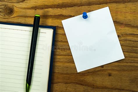 La Nota Del Papel En Blanco Sobre El Fondo De Madera Con El Perno Azul